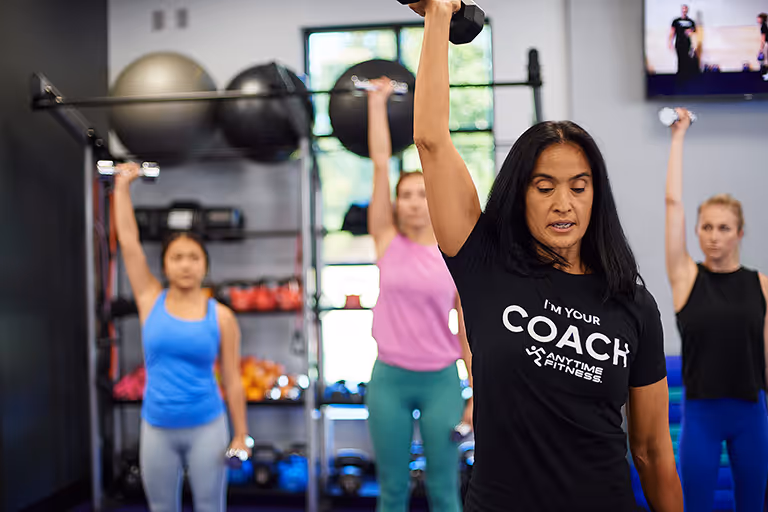 A coach woman holding up dumbbells 