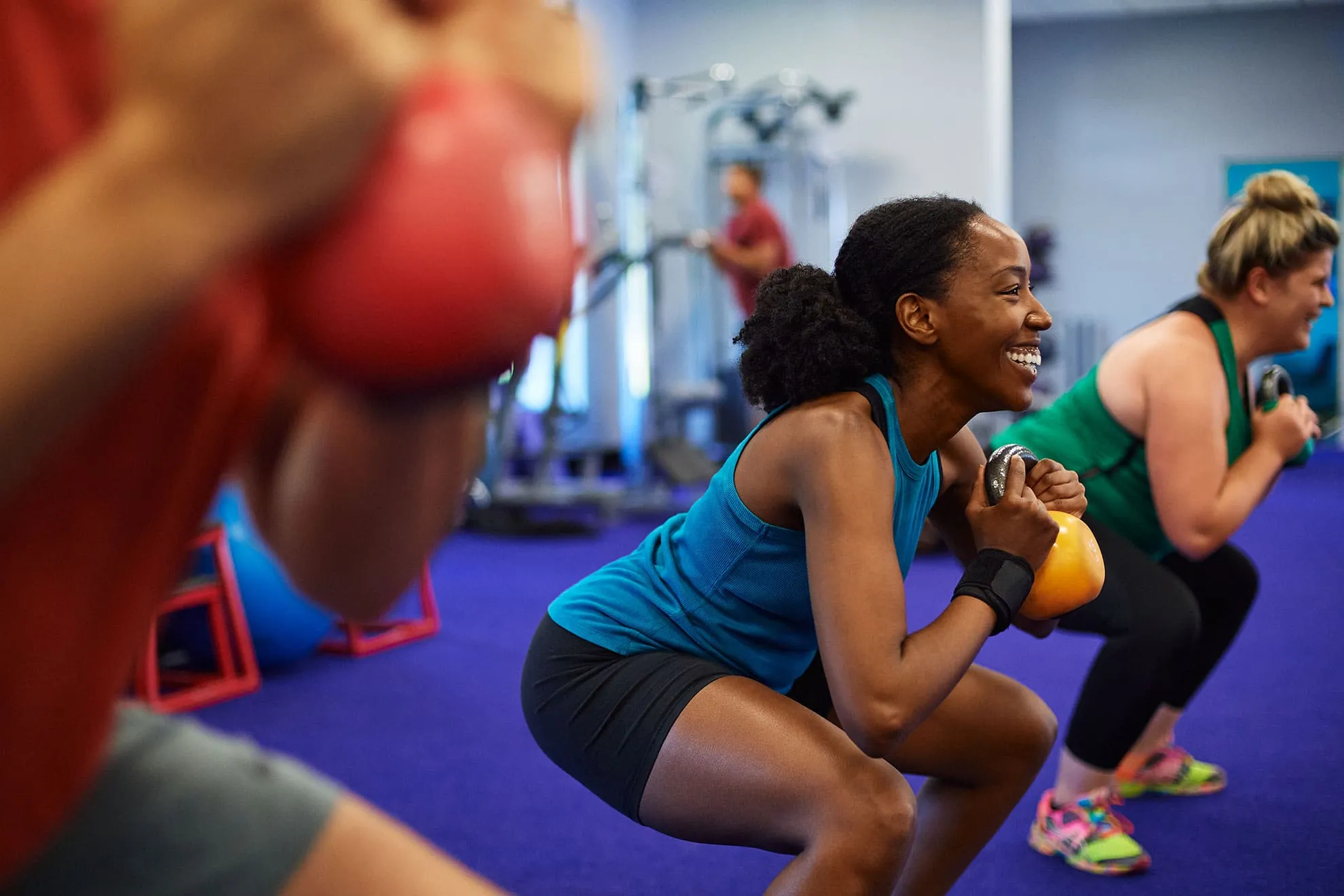 People performing kettlebell exercises in a gym.